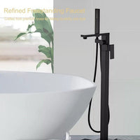 Black freestanding faucet next to a white bathtub with a plant in the background