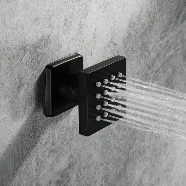 Black shower head mounted on a gray tiled wall with water flowing.
